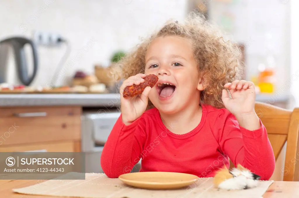 Adorable girl eating sausage.