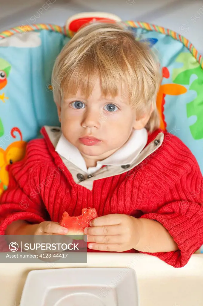 Sad boy eating watermelon.