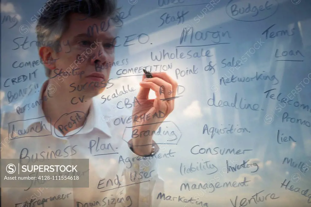 Businessman writing business words onto glass