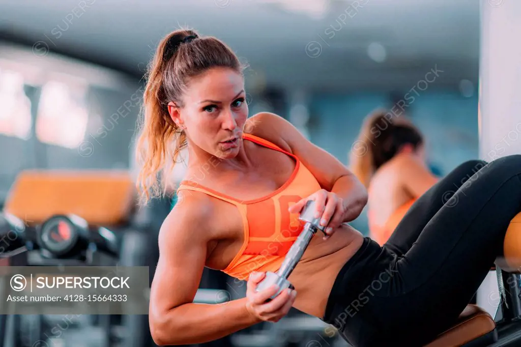 Female athlete doing sit ups with dumbbell SuperStock