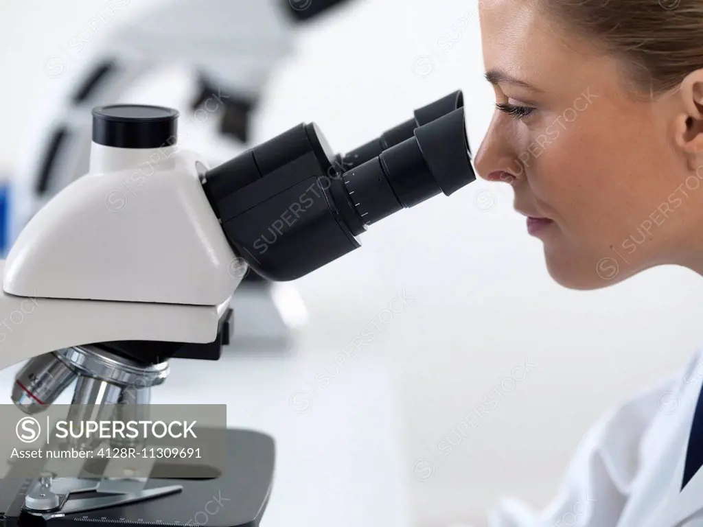 Female scientist using a microscope.