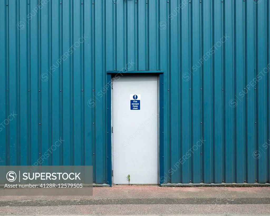 Fire escape exit in metal clad industrial building. Photographed in Trafford Park, Greater Manchester, UK