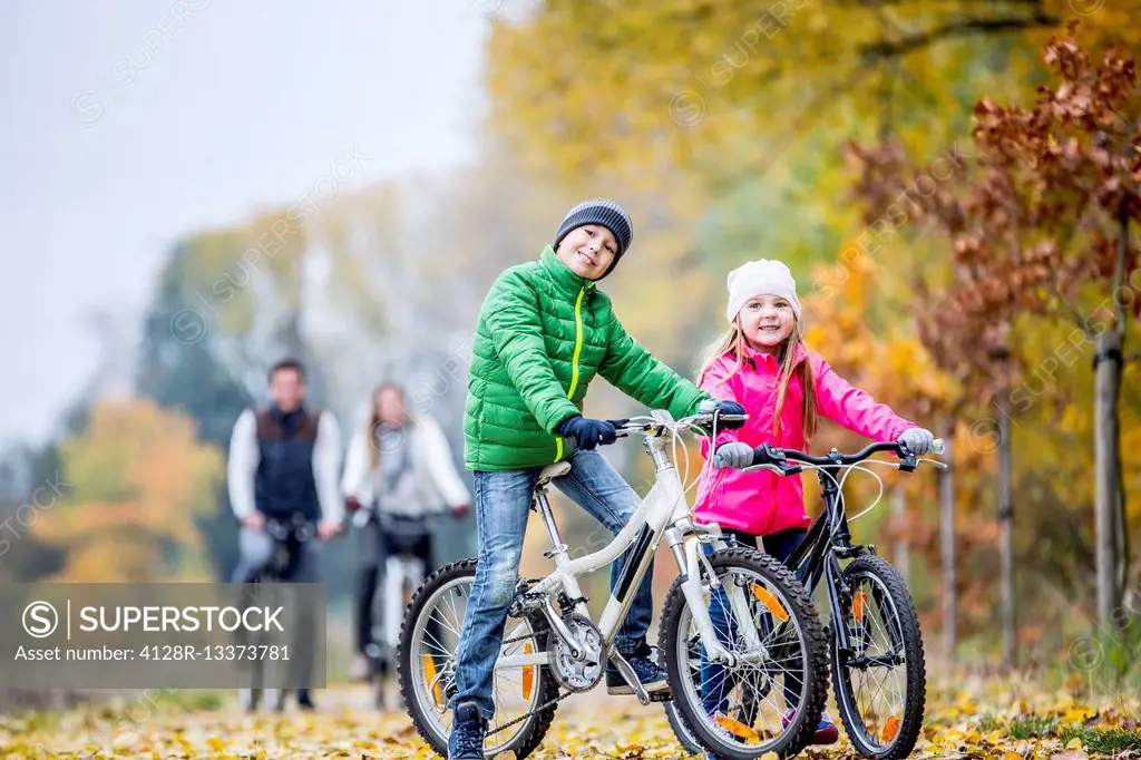 MODEL RELEASED. Siblings cycling in autumn, portrait.