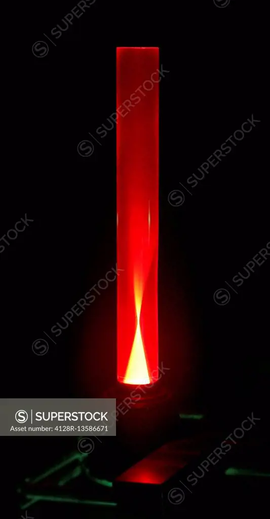 Laser and ruby rod. Experiment with a green laser beam being used to induce red luminescence in a rod of artificial ruby. Synthetic ruby is used to ma...