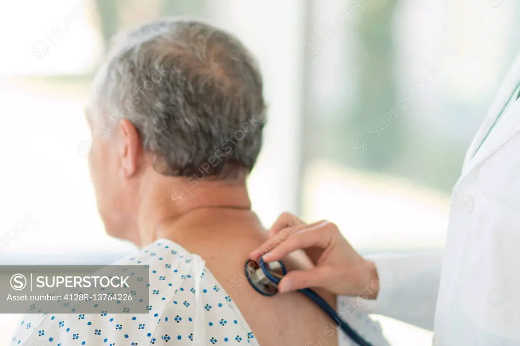 Female doctor using stethoscope on male patient.