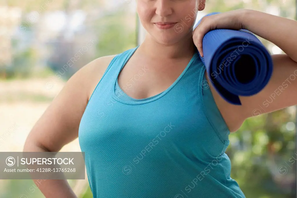 Woman holding yoga mat, cropped.