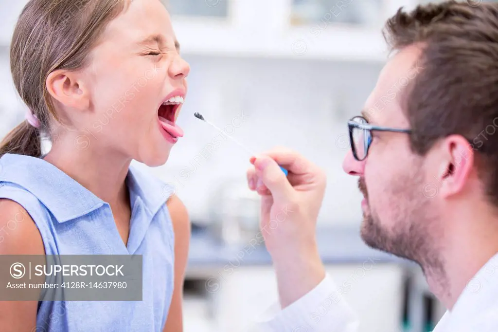 Doctor taking a swab from a girl's mouth