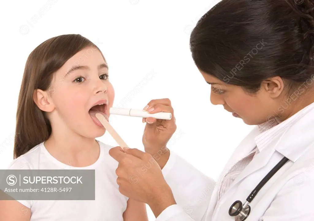 Throat examination. Paediatrician using a tongue depressor and a penlight to examine a girl´s throat.