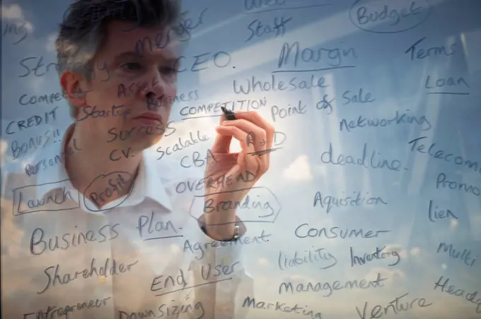 Businessman writing business words onto glass