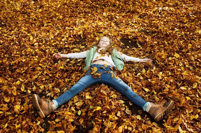 Girl lying in Autumn leaves