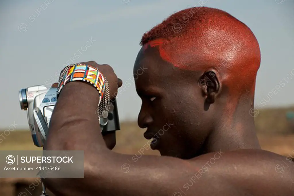 masai warrrior ( a moran ) using a video camera, kenya.