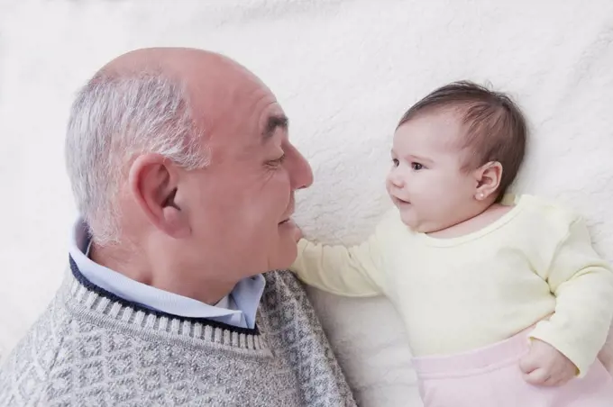 Grandfather Playing with New Baby Granddaughter on Bed