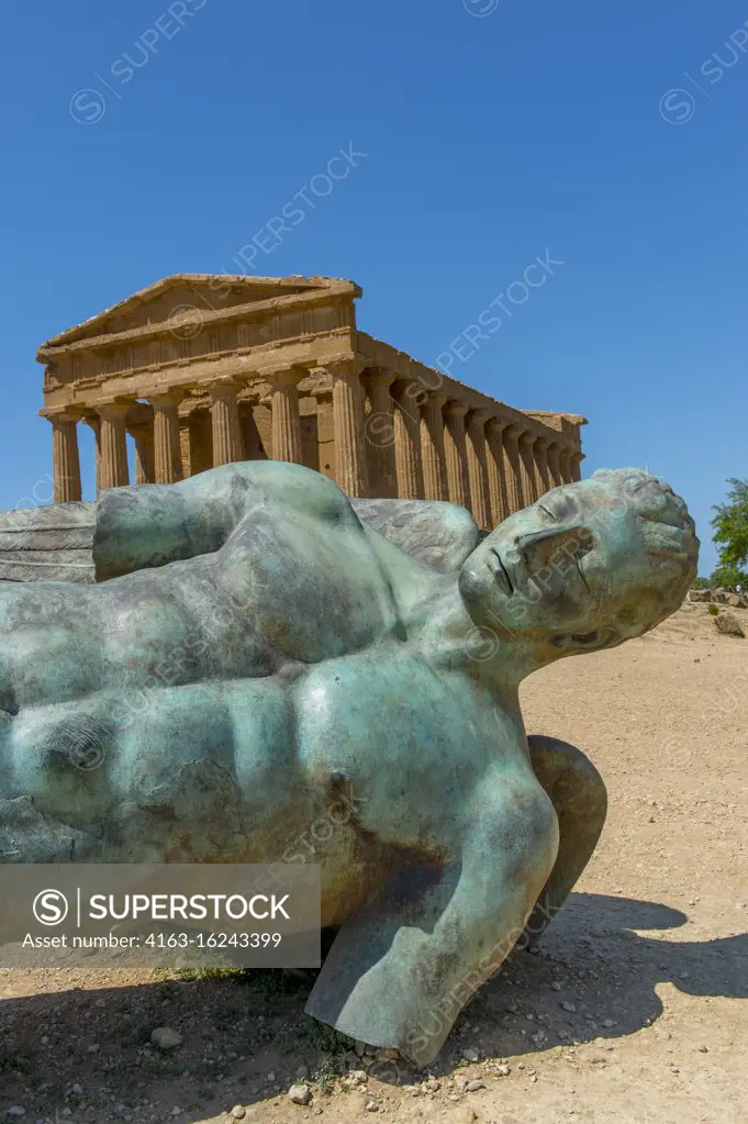 Ikaro caduto (fallen Icarus) bronze sculpture by Polish artist Igor Mitoraj in front of the Temple of Concordia (Greek: Harmonia) , built c.440-430 BC, which is an ancient Greek temple of the ancient city of Akragas, located in the Valle dei Templi in Agrigento on the island of Sicily in Italy.