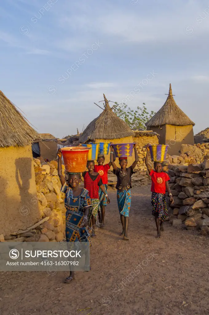 Dogon girls bringing water from a community well back to their homes in the Djiguibombo Dogon village in the Bandiagara area, Dogon country in Mali, West Africa.