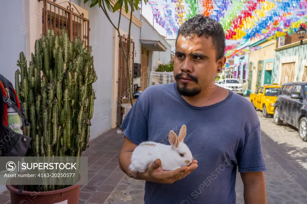 A man with his pet rabbit in a street of Barrio de Jalatlaco, in Oaxaca City, Mexico.