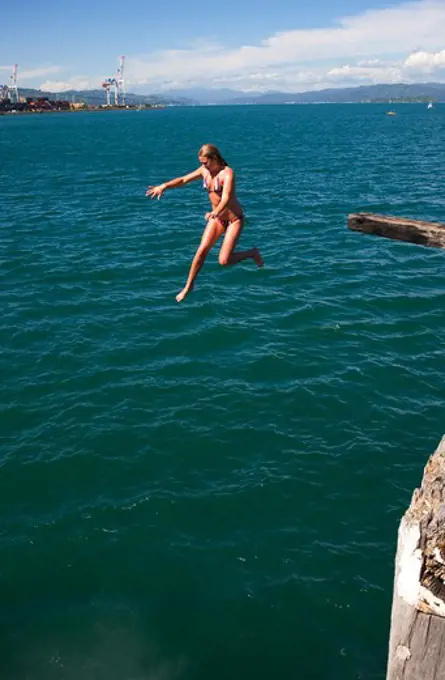 NEW ZEALAND, NORTH ISLAND, WELLINGTON, LAMBTON HARBOUR, GIRL JUMPING INTO WATER