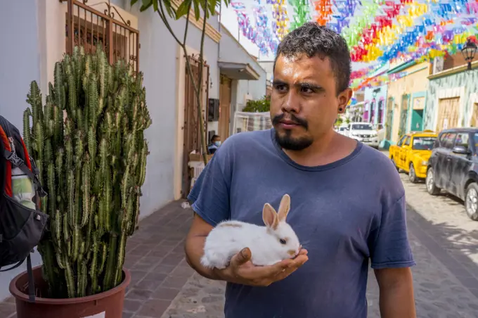 A man with his pet rabbit in a street of Barrio de Jalatlaco, in Oaxaca City, Mexico.