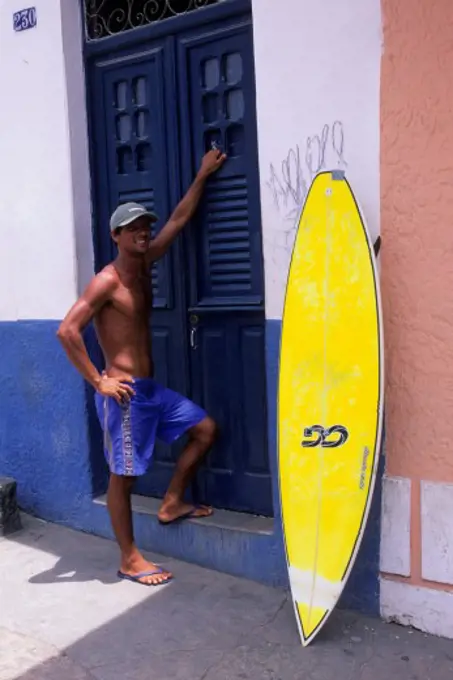 BRAZIL, NEAR RECIFE, OLINDA, STREET SCENE, MAN WITH SURFBOARD