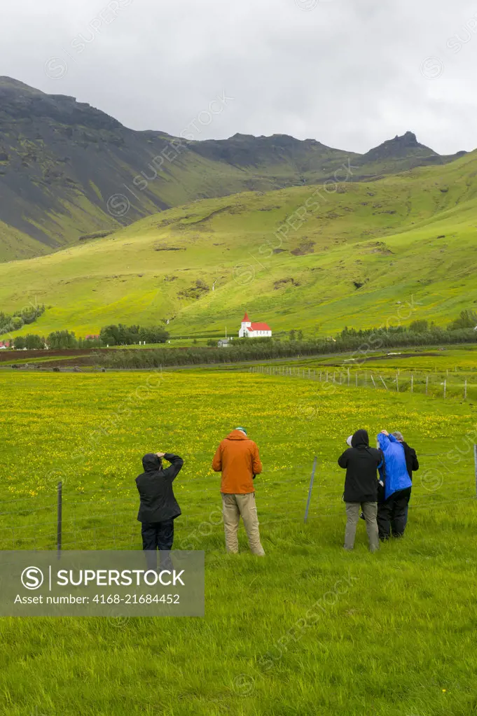 People photographing a farm and church at Asolfsskali in the south of Iceland.