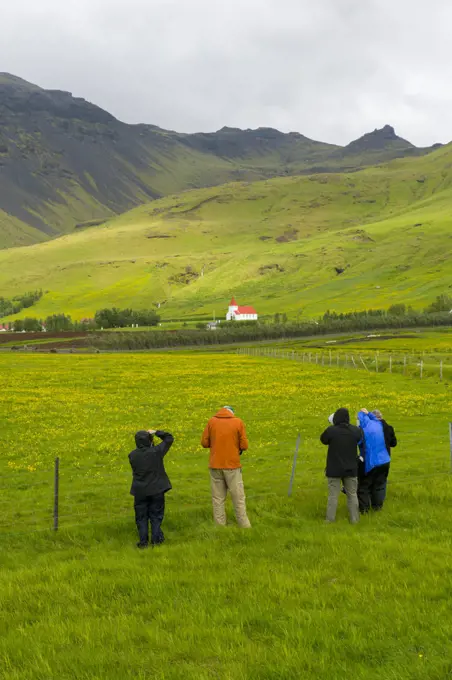 People photographing a farm and church at Asolfsskali in the south of Iceland.