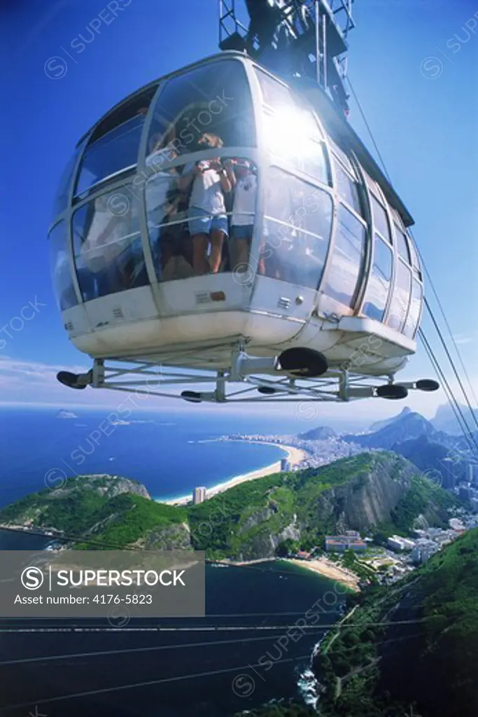 Cable car loaded with passengers nearing Sugar Loaf with Rio below