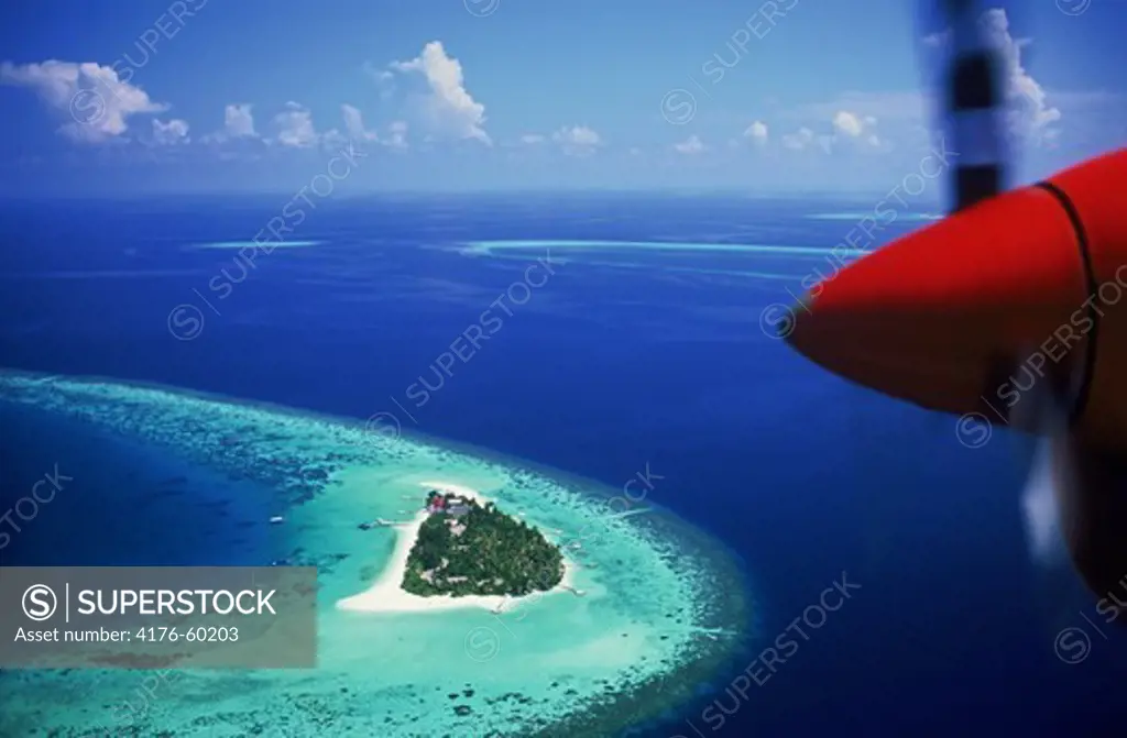 Aerial view with plane prop over Mayafushi Island in Maldive Islands amid blue Indian Ocean waters of North East Ari Atoll