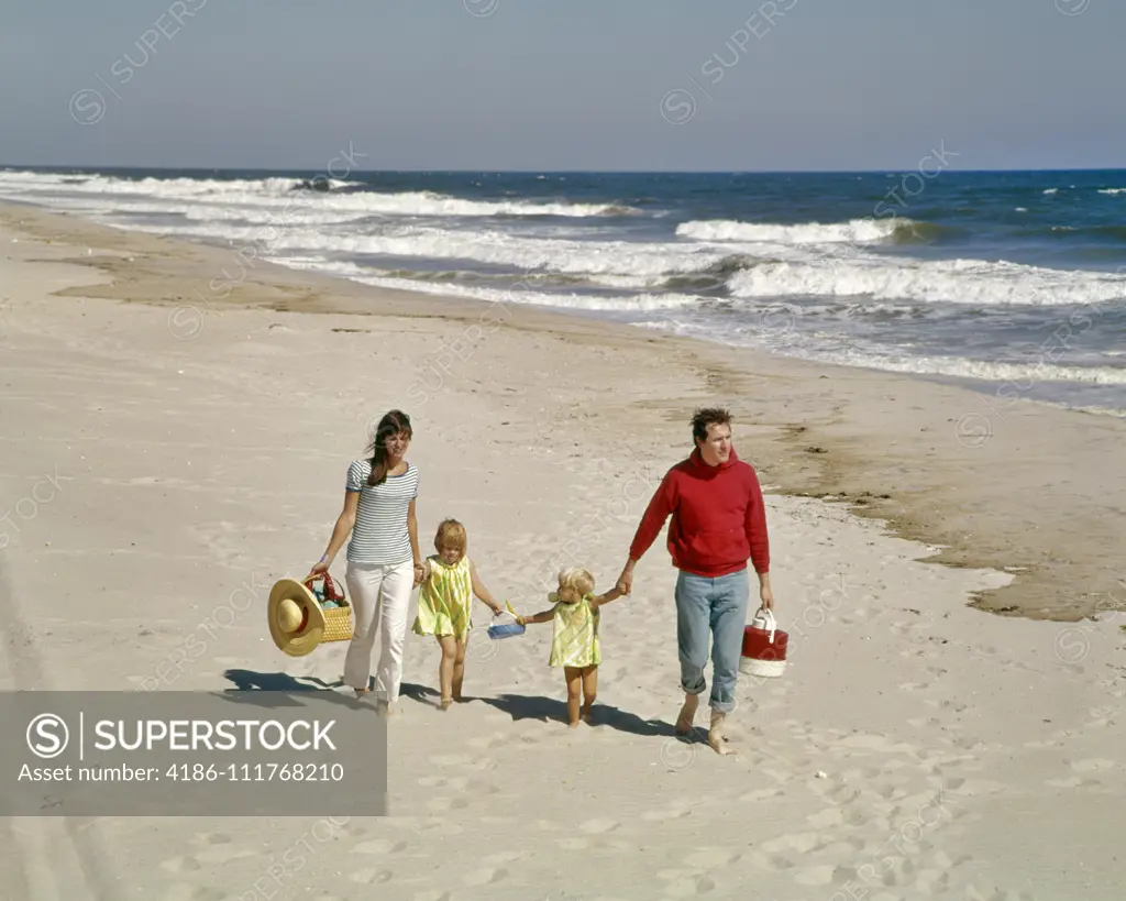 1960'S 1970'S FAMILY WALKING TOGETHER HAND HOLDING ON BEACH BY OCEAN SHORE WATER OUTDOOR MOTHER FATHER SON DAUGHTER