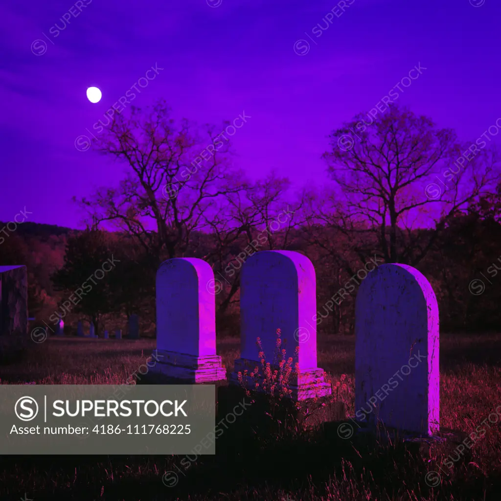 1980s THREE TOMBSTONES IN DARK CEMETERY UNDER BRIGHT MOON WITH PURPLE FILTER GRAPHIC EFFECT