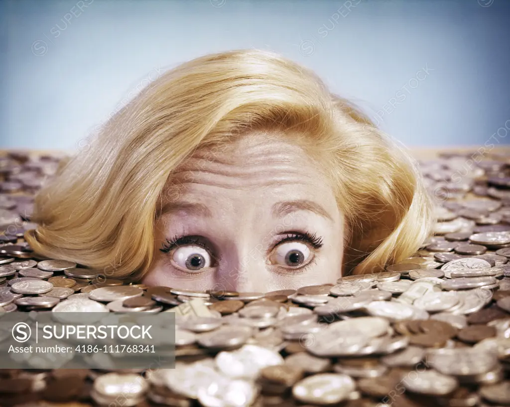 1960s PANICKED BUG-EYED BLOND YOUNG WOMAN BURIED UP TO HER NOSE IN PILE OF COINS AND CURRENCY