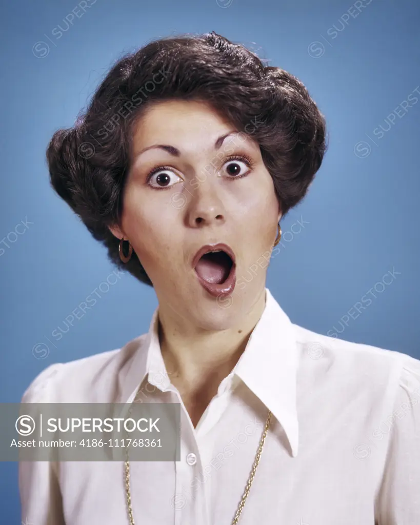 1970s PORTRAIT BRUNETTE WOMAN WITH SURPRISED SHOCKED ALARMED FACIAL EXPRESSION MOUTH AND EYES WIDE OPEN LOOKING AT CAMERA