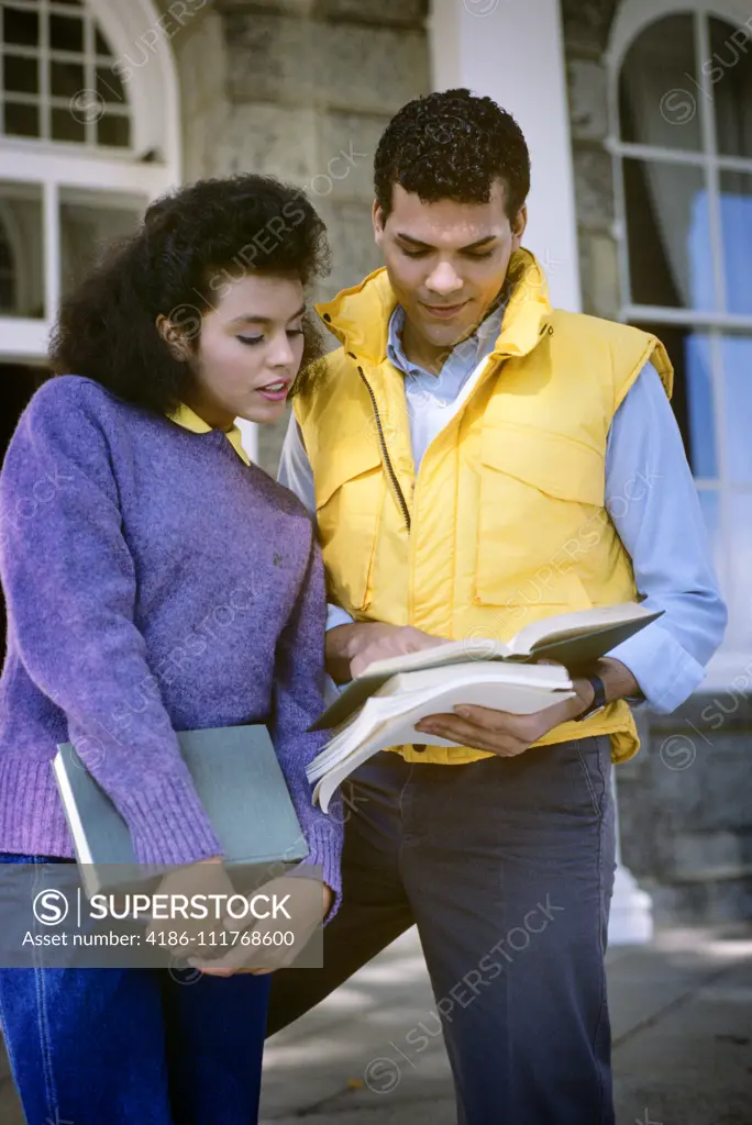 1980s AFRICAN AMERICAN COLLEGE COUPLE LOOKING AT TEXTBOOK