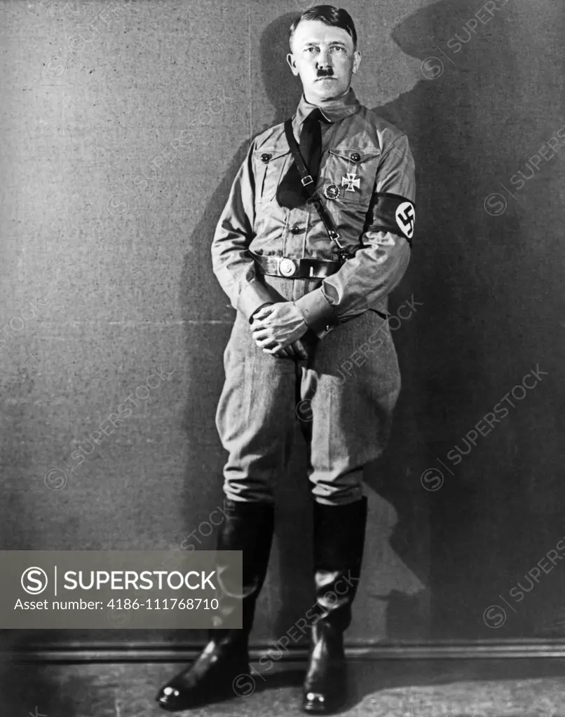 1920s 1930s FULL FIGURE STANDING ADOLF HITLER DER FUHRER WEARING BROWN SHIRT UNIFORM WITH SWASTIKA ARM BAND LOOKING AT CAMERA