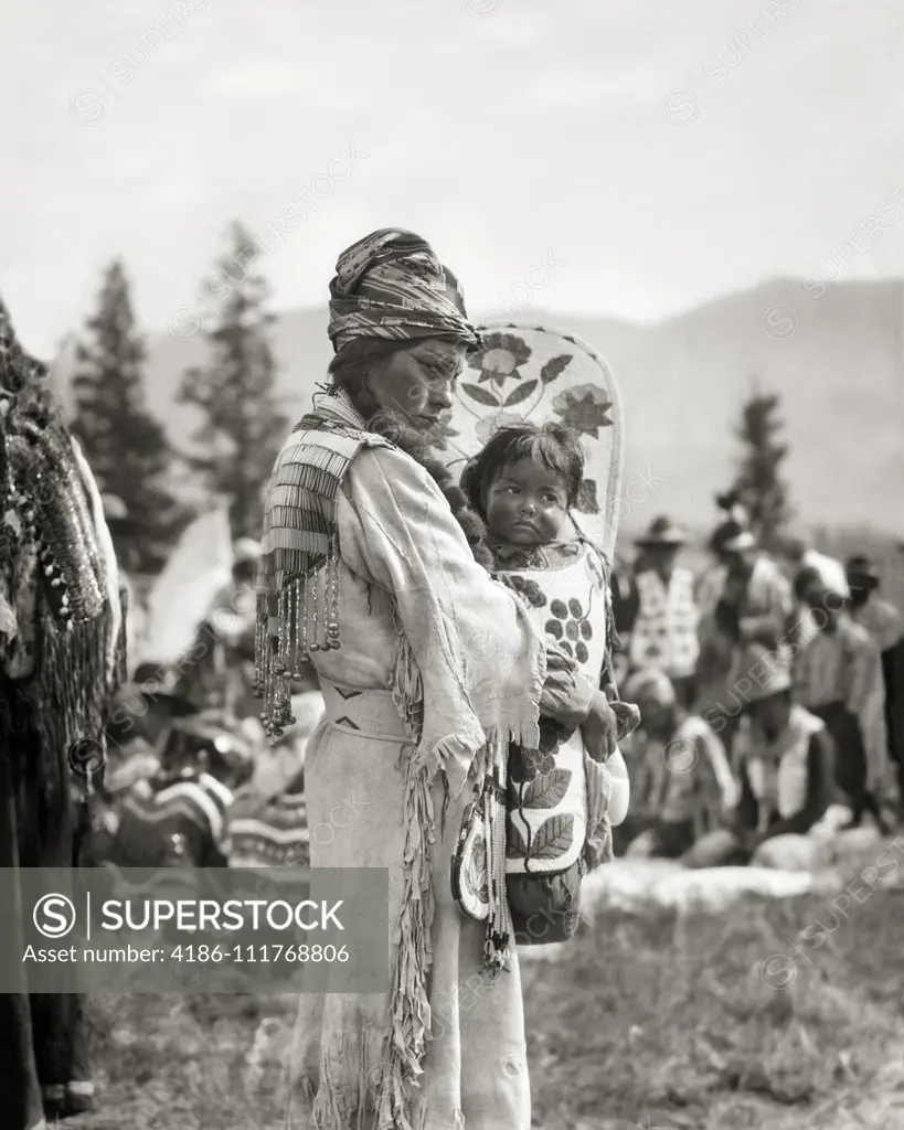 1920s 1930s NATIVE AMERICAN STONEY SIOUX INDIAN WOMAN MOTHER IN BEADED BUCKSKIN DRESS HOLDING BABY BOY GIRL IN PAPOOSE CANADA