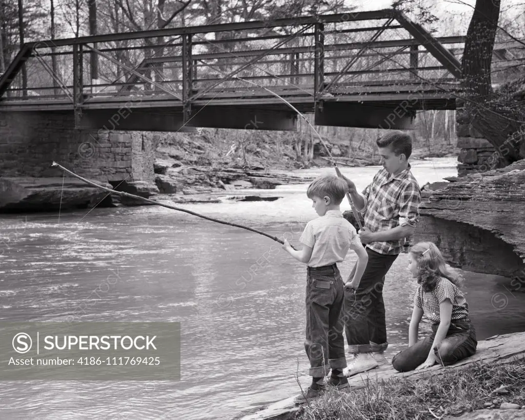 1950s YOUNG GIRL SITTING BESIDE CREEK BY ROAD BRIDGE WATCHING TWO
