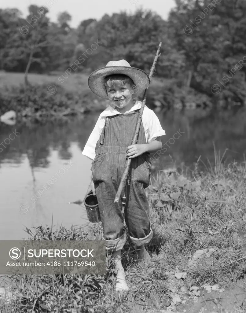 1960s BABY GIRL WEARING FISHING HAT HOLDING NET AND REEL FISHING