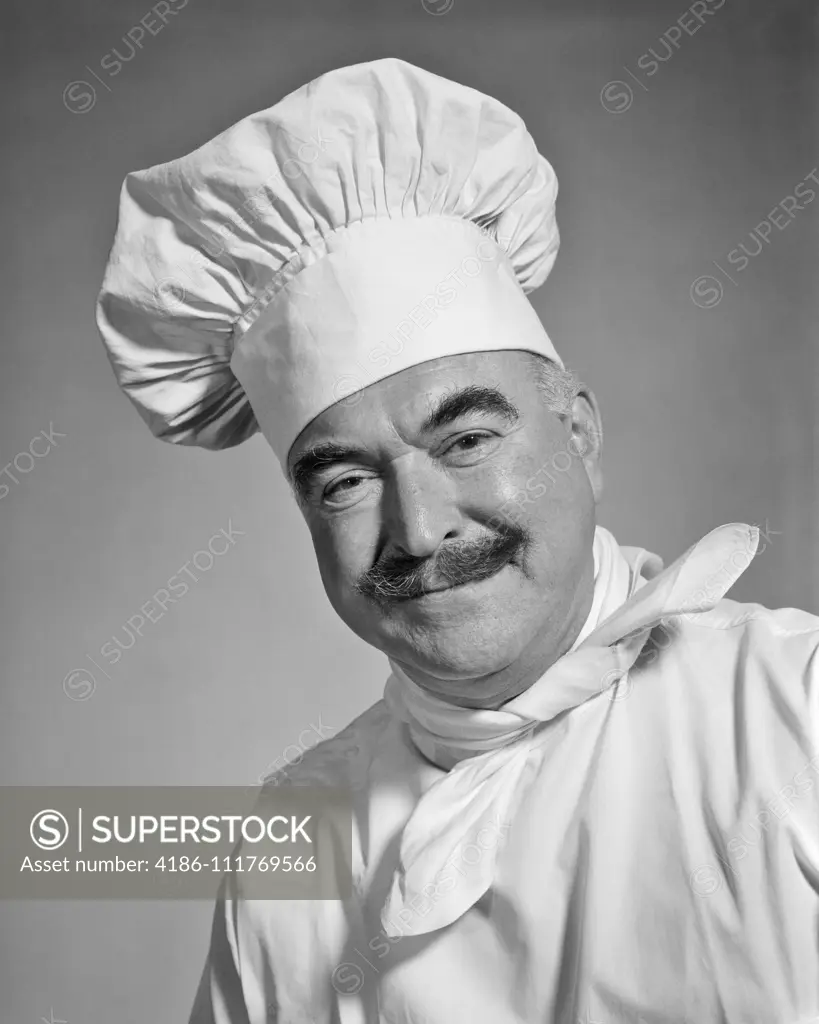 1960s SMILING MAN CHEF WITH MUSTACHE LOOKING AT CAMERA WEARING WHITE TOQUE CHEFS HAT NECKERCHIEF AND LINEN UNIFORM JACKET