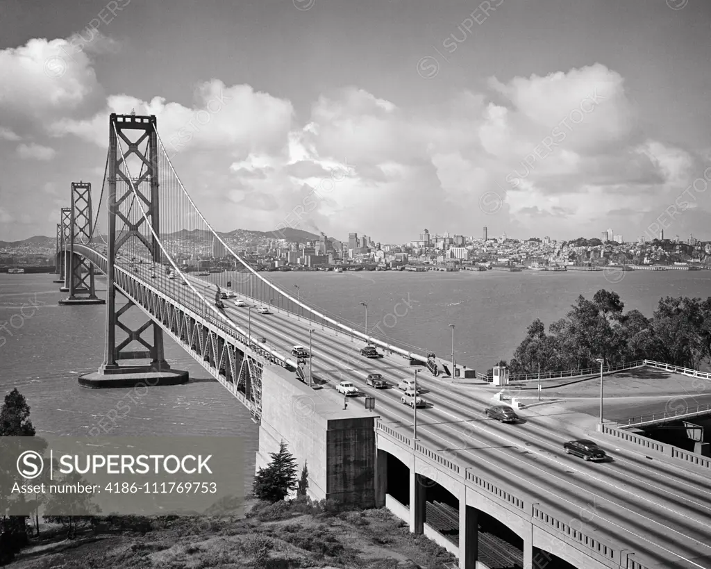 1950s VIEW OF SAN FRANCISCO PAST AUTOMOBILES CROSSING BAY BRIDGE SEEN FROM OAKLAND CALIFORNIA USA