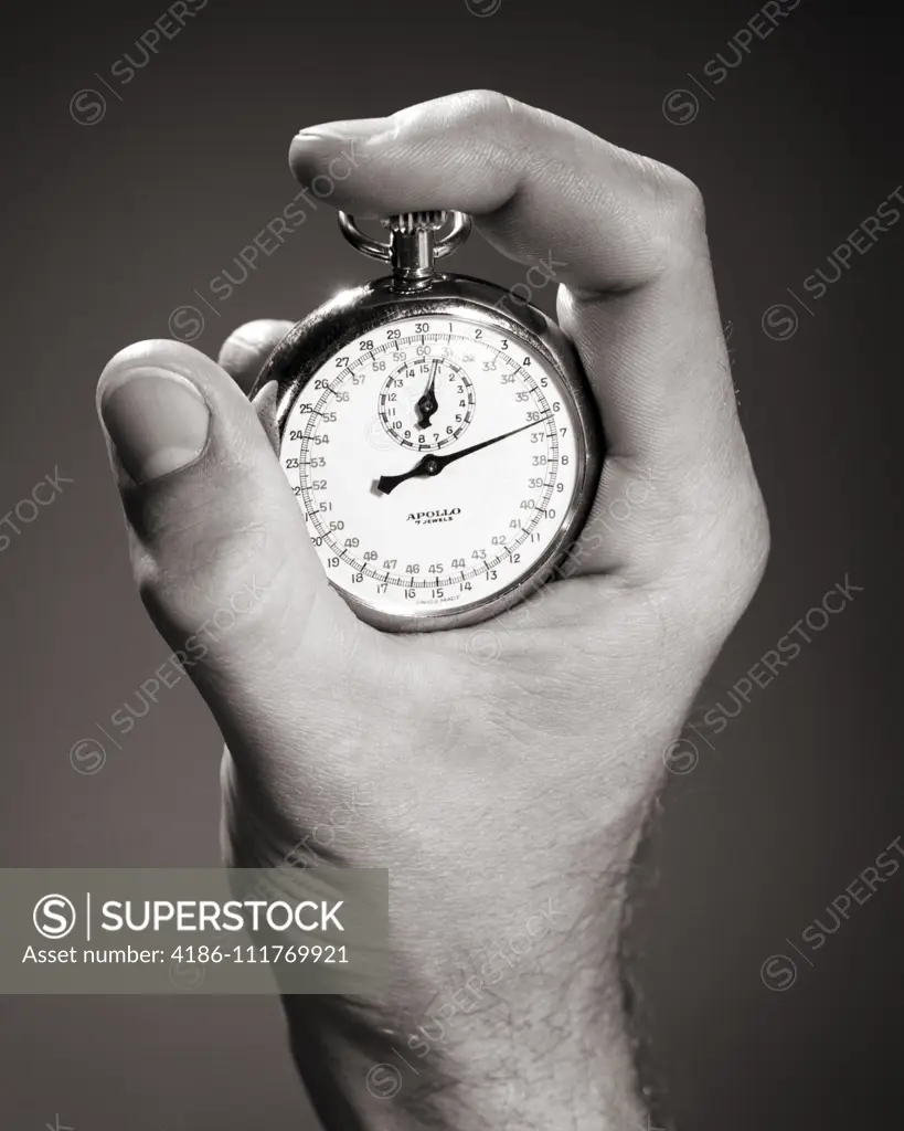 1960s MALE HAND HOLDING A STOPWATCH