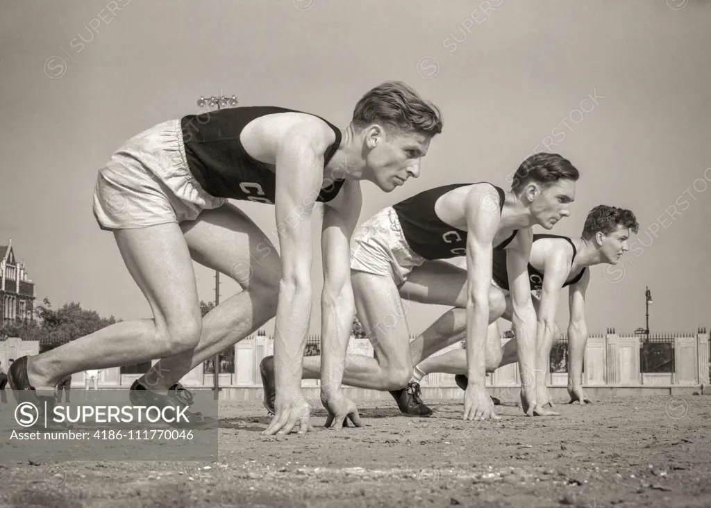 1940s THREE RUNNERS AT STARTING LINE OF FOOT RACE TRACK AND FIELD