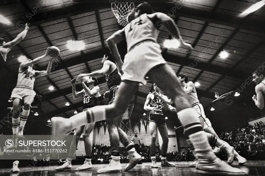 1960s 1970s COLLEGIATE BASKETBALL GAME PLAYERS UNDER THE HOOP SHOOTING TO SCORE EXTREME LOW ANGLE BACK VIEW