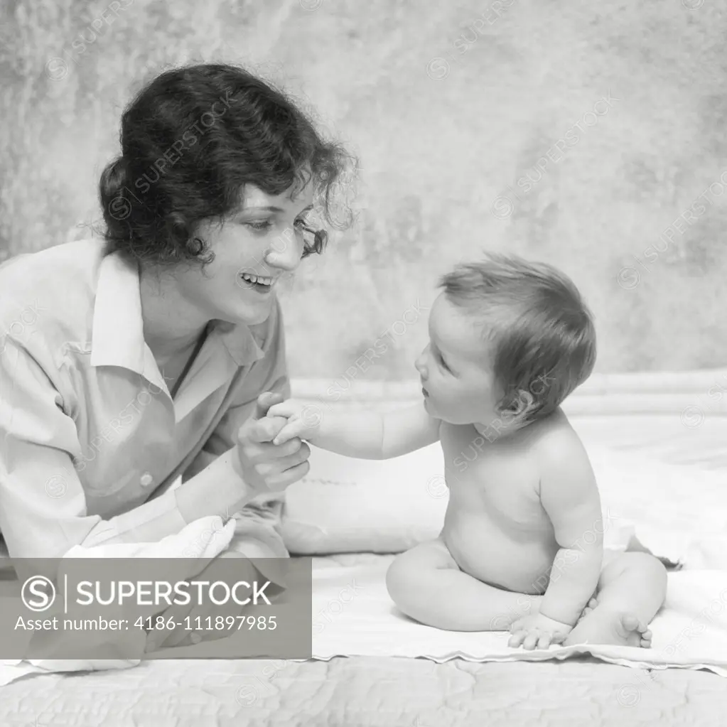 1920s SMILING BRUNETTE WOMAN MOTHER HOLDING HANDS FINGERS WITH BABY GIRL