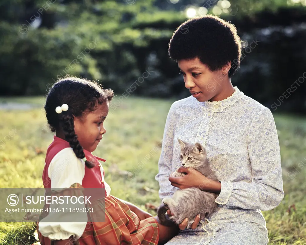 1970s 1960s MOTHER AND DAUGHTER IN BACKYARD MOTHER HOLDING A TABBY KITTEN