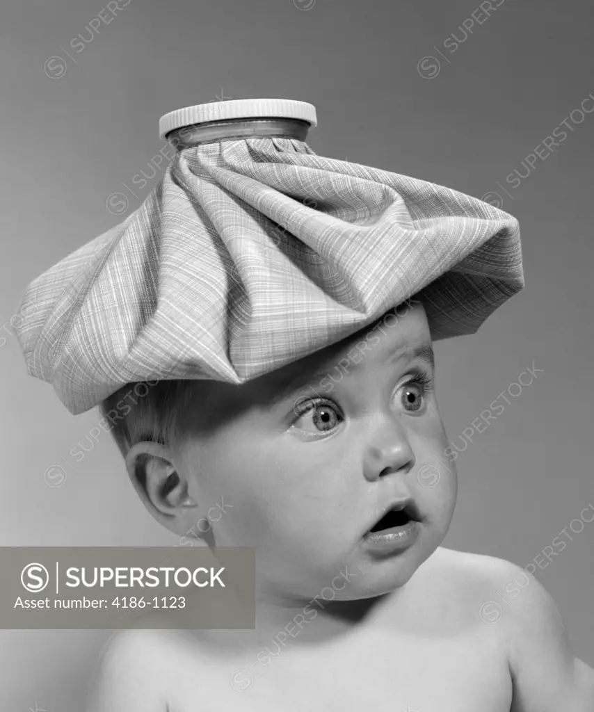 1960S Portrait Baby Wide-Eyed With Mouth Open & Ice Pack On Head Looking Off To Side