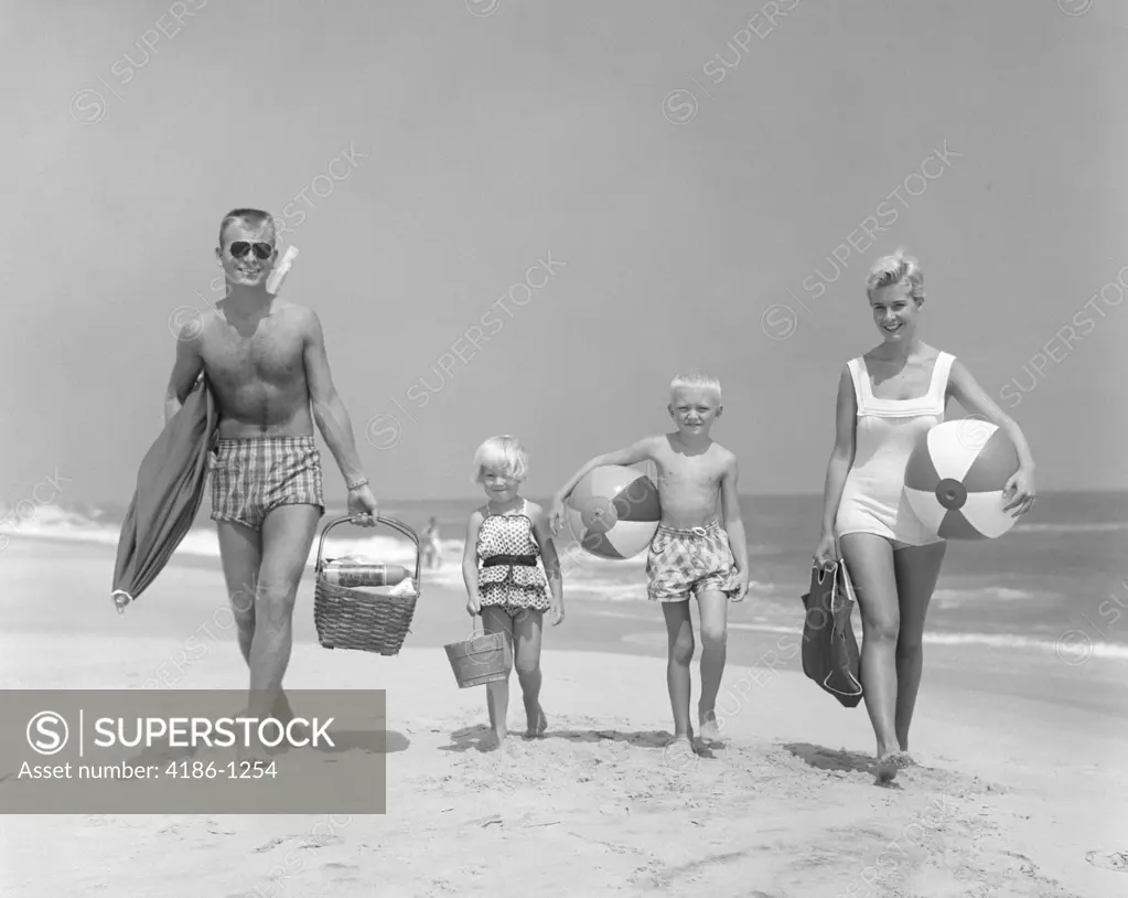 1950S Family Of Four Walking Towards Camera With Beach Balls Umbrella Picnic Basket And Sand Bucket