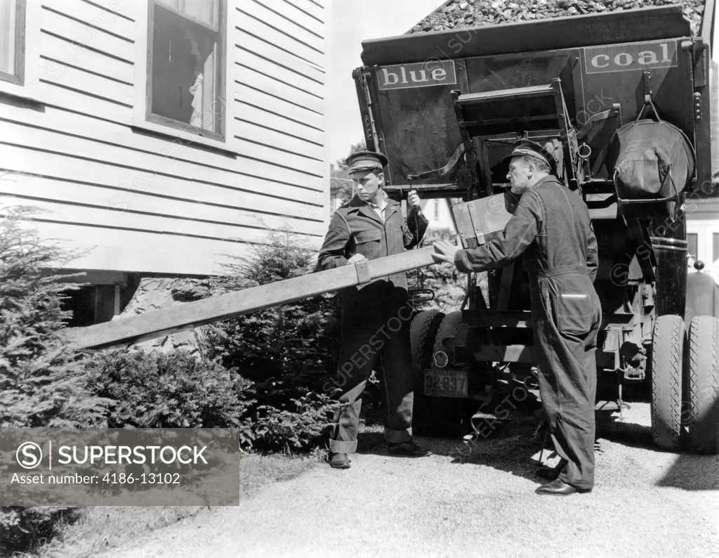 1930S 1940S 1950S Coal Truck With Two Service Men Making Home Delivery Coal Chute Into Basement Of Suburban House Lift-Bed Truck