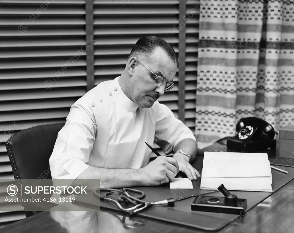 1940S Doctor Sitting At Desk Writing Prescription