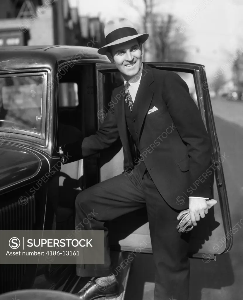 1930S Smiling Man In Suit And Hat Holding Gloves Stepping Into Automobile Driver Seat