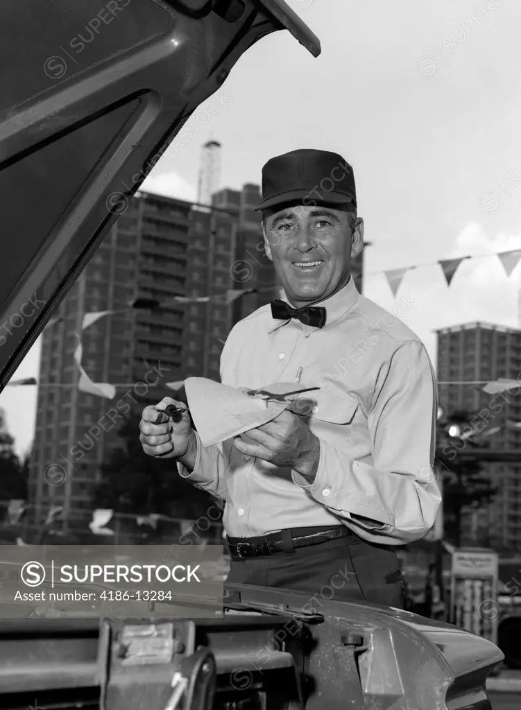 1960S Smiling Gas Station Attendant In Uniform Wiping Off Dipstick After Checking Oil