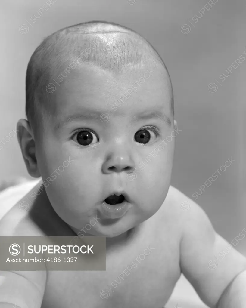 1960S Close-Up Of Baby Lying On Stomach Wide-Eyed With Mouth Open