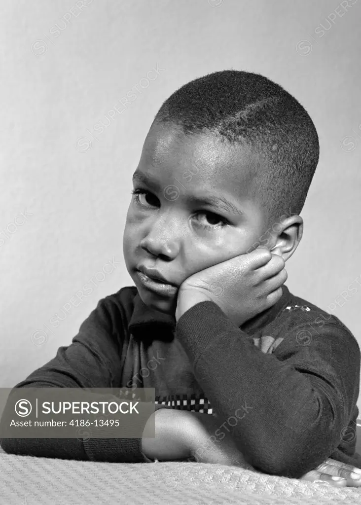 Portrait Of Sad Unhappy African-American Boy Head Resting On Hand Studio